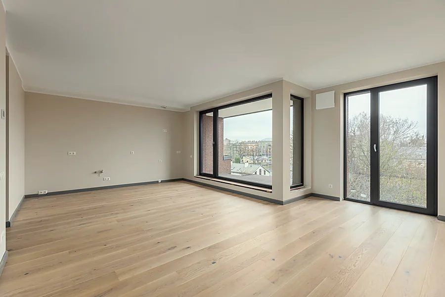 Stūra dzīvojamā istaba ar panorāmas logu un balkona durvīm